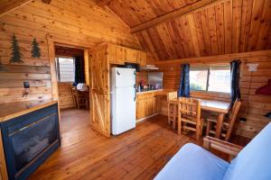 a kitchen and dining room of a log cabin with a refrigerator at Redwood Coast Cabins and RV Resort in Eureka