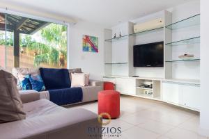 a living room with a couch and a tv at BZ36 Casa com piscina privativa - Centro de Búzios in Búzios