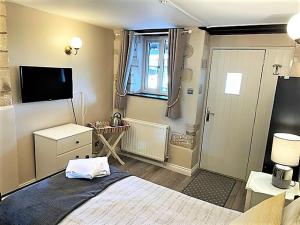 1 dormitorio con 1 cama grande y TV en Cotswold Merrymouth Inn en Bourton on the Water