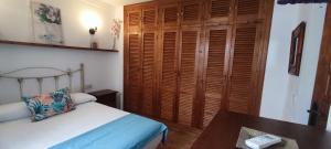 een slaapkamer met een bed en een houten kast bij Estudio Patio San Paulino II in Barbate