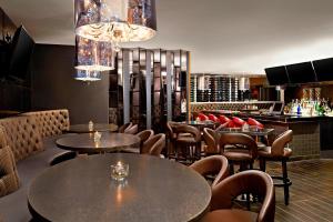 a restaurant with tables and chairs and a bar at Four Points by Sheraton Hotel & Suites Calgary West in Calgary