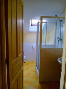 porta aperta per un bagno con doccia e lavandino di Casa Los Lomas ad Arenas de Iguña