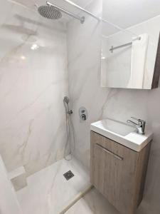een witte badkamer met een wastafel en een douche bij Beautiful 1 bedroom flat near Olympic Stadium in Athene