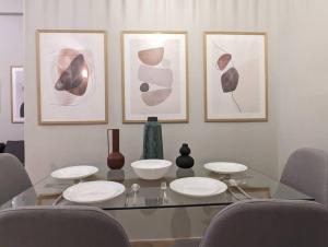 een glazen tafel met vier stoelen en schilderijen aan een muur bij Beautiful 1 bedroom flat near Olympic Stadium in Athene