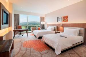 um quarto de hotel com duas camas e uma secretária e uma televisão em Le Meridien Putrajaya em Putrajaya