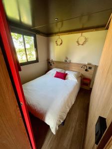 a bedroom with a large white bed with a red pillow at DOMAINE DES GALINACES ROULOTTE LA ROUSSETTE 2-4P in Marigny-lès-Reullée
