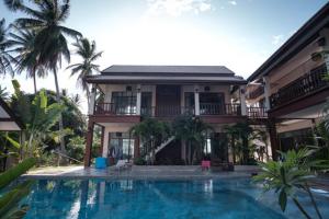 a house with a swimming pool in front of a house at Coconut Tree Homestay in Ban Wa Thon