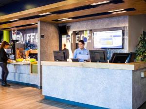 a woman standing at a counter in a restaurant at ibis budget Paris Porte de Pantin in Pantin