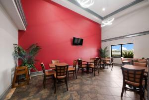 un restaurante con paredes rojas, mesas de madera y sillas en SureStay Plus Hotel by Best Western San Antonio North, en San Antonio