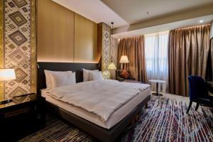 エレバンにあるRadisson BLU Hotel Yerevanの大きなベッドとデスクが備わるホテルルームです。