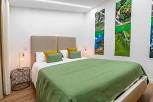 sypialnia z dużym łóżkiem i zielonym kocem w obiekcie Foral Dreams w mieście Fajã de Cima