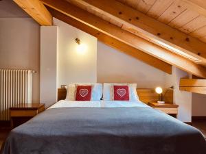 um quarto com uma cama grande e 2 almofadas vermelhas em Elga Residence - Relax in Alta Valtellina - Bormio em Valdisotto