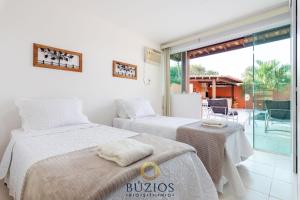 two beds in a room with a balcony at BZ36 Casa com piscina privativa - Centro de Búzios in Búzios +28 photos