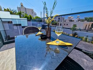 stół z dwoma kieliszkami wina na balkonie w obiekcie Giorgis Luxury Apartments w Ajia Napa
