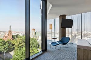 Cette chambre dispose d'une chaise bleue et offre une vue sur la ville. dans l'établissement Courtyard by Marriott Szczecin City, à Szczecin