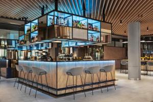 a bar in a restaurant with stools around it at Courtyard by Marriott Szczecin City in Szczecin