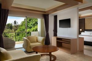 sala de estar con sofá, TV y cama en Sthala, A Tribute Portfolio Hotel, Ubud Bali en Ubud