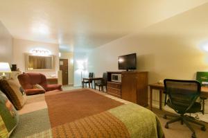 Habitación de hotel con cama, escritorio y TV. en Venture Inn en Libby