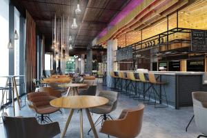 a restaurant with tables and chairs and a bar at Moxy Szczecin City in Szczecin