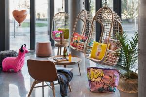 a living room with chairs and a table and a rattan basket chair at Moxy Szczecin City in Szczecin