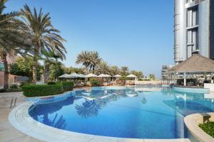a large swimming pool with palm trees and a building at Sheraton Abu Dhabi Hotel & Resort in Abu Dhabi