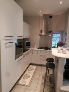 una cucina con armadi bianchi, bancone e sgabello di Blue House a Borgomanero
