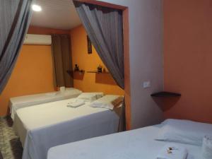 2 camas en una habitación de hotel con cortinas en Pousada Alto das Galés, en Maragogi