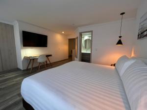 a hotel room with a large white bed and a desk at Suites 109 GH Usaquén in Bogotá