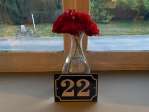 a vase with red flowers sitting on a window sill at 22 in Érin