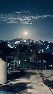 a view of a city at night with the moon at Cómodo y muy relajante alojamiento a 5 minutos de la playa in Acapulco