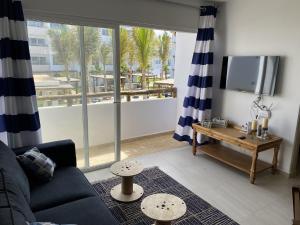 a living room with a couch and a tv and a balcony at Nuevo y Muy Bonito Departamento Con Vista a la Alberca - Residencial Almarena I in Mazatlán