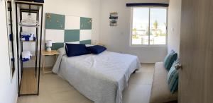 a bedroom with a bed with blue pillows and a window at Nuevo y Muy Bonito Departamento Con Vista a la Alberca - Residencial Almarena I in Mazatlán +13 photos