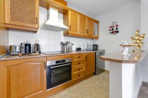 a kitchen with wooden cabinets and a counter top at Penthouse Naomi with two terraces, private solarium, sea view, swimming pool, with underground parking, pets allowed in Orihuela Costa