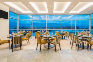 un restaurante con mesas, sillas y ventanas grandes en Four Points by Sheraton Cuenca en Cuenca