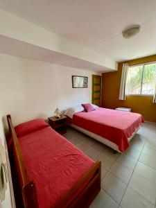 a bedroom with two beds with red sheets and a window at Hotel Village Termas de Dayman in Termas del Daymán +80 photos