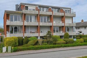 un edificio de apartamentos con arbustos frente a una calle en Haus-am-Deich-Wohnung-13, en Dahme