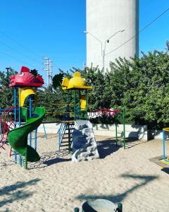 a playground with a slide in the sand at Acogedora casa en ica in Ica