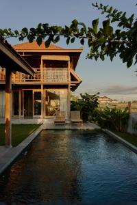 uma casa com piscina em frente a uma casa em Bruann residence villa 1, Seseh, Perenenan, amazing sunset view and privacy, 2 bedroom em Munggu