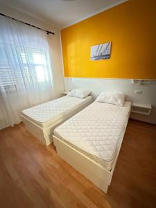 two beds in a room with a yellow wall at Apartments with a parking space Mali Losinj (Losinj) - 15858 in Mali Lošinj