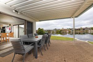 a table and chairs on a patio with a view of the water at 23 Elouera Crescent in Forster