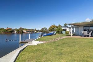 a house with a dock next to a body of water at 23 Elouera Crescent in Forster