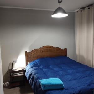 a bed with a blue comforter and a lamp at Departamento 1 Dormitorio 1 Baño Valparaíso in Valparaíso