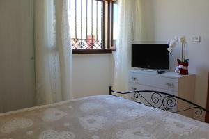 - une chambre avec un lit et une télévision sur une commode dans l'établissement Villa Rosa zona Torre San Giovanni, à Torre San Giovanni