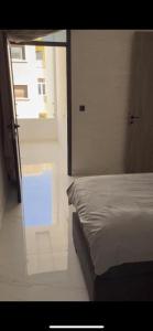 a bedroom with a bed and a glass door with a window at Appartement Nador Jadid in Nador