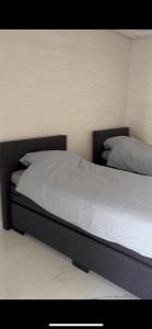 um quarto com uma cama com lençóis brancos e almofadas em Appartement Nador Jadid em Nador