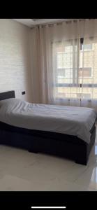 1 cama en un dormitorio con ventana en Appartement Nador Jadid, en Nador