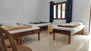a room with two beds and a chair and a window at HOTEL PINE RESORT NETALA in Uttarkāshi