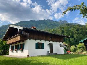 una pequeña casa blanca con montañas en el fondo en Ferienhaus Lois & Lisl, en Schleching
