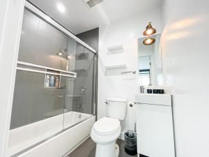 a white bathroom with a shower and a toilet at Spacious 4BR Townhouse in Mid City - WH-C2 in Los Angeles