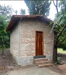 ein kleines Backsteingebäude mit einer Holztür in der Unterkunft Cantinho HAKUNA MATATA-Vale do Capão a 5 min da Vila in Vale do Capao